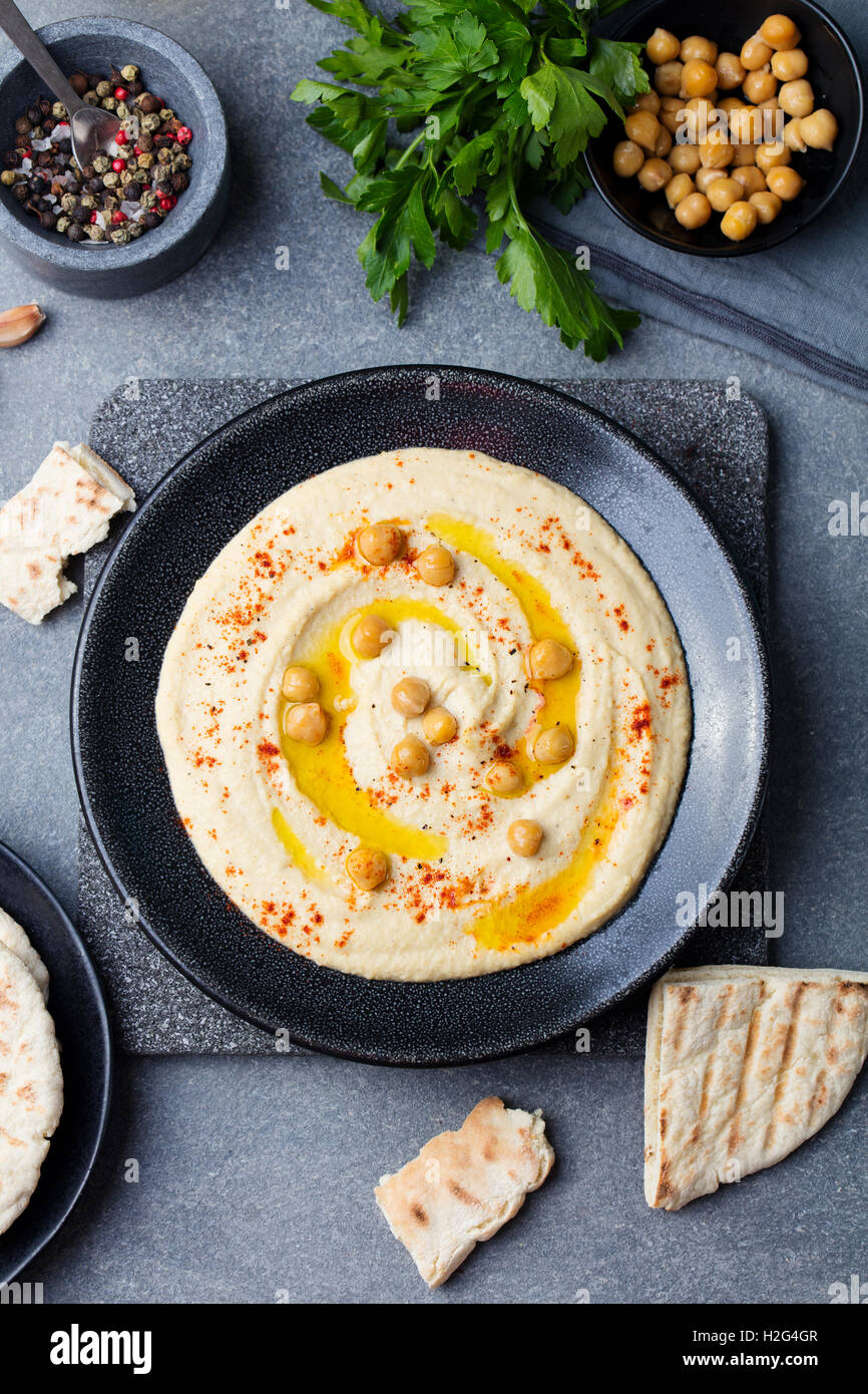 Hummus, Kichererbsen dip, mit Gewürzen und Pita, Fladenbrot in einer schwarzen Platte. Ansicht von oben Stockfoto