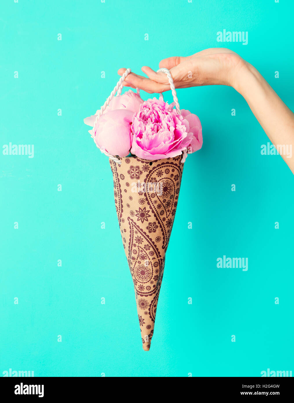 Blumenstrauß in weiblicher Hand auf eine türkisfarbene Wand Hintergrund Pfingstrosen. Textfreiraum Stockfoto