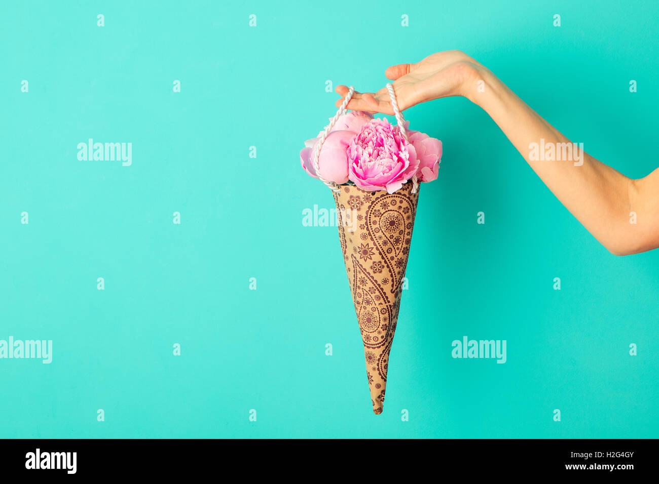 Blumenstrauß in weiblicher Hand auf eine türkisfarbene Wand Hintergrund Pfingstrosen. Textfreiraum Stockfoto