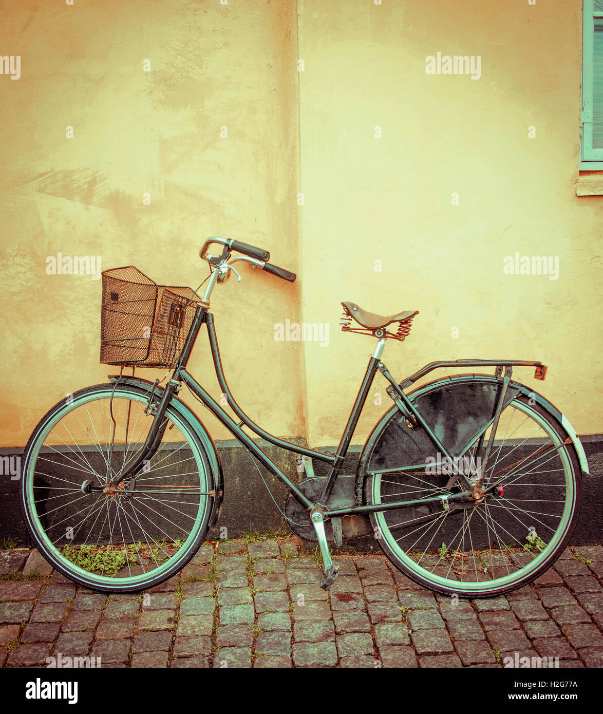 Eine einzigartige grüne Rad anliegt eine leuchtend gelbe Wand illustrieren Kopenhagen Dänemark romantische Fahrradkultur. Stockfoto