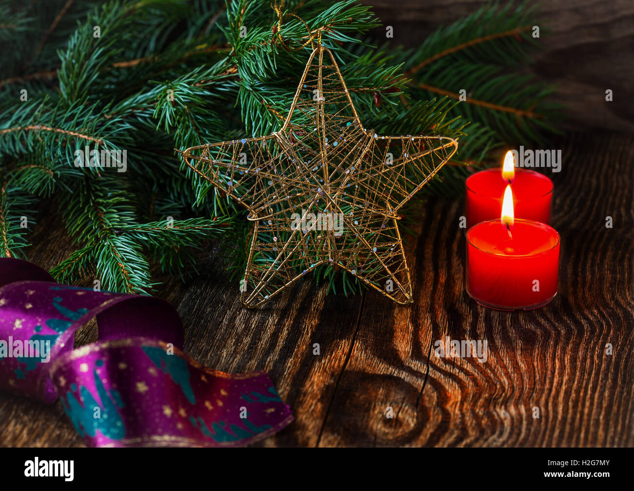 Weihnachts-Dekoration. Weihnachtskerzen und Tannenzweig auf rustikalen