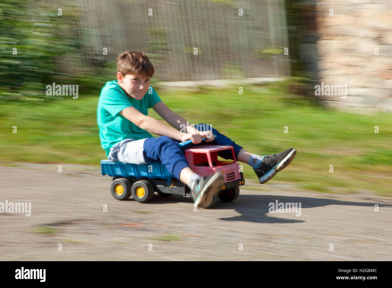 Junge reiten bergab auf Spielzeug LKW Stockfoto