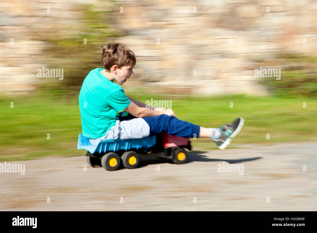 Junge reiten bergab auf Spielzeug LKW Stockfoto