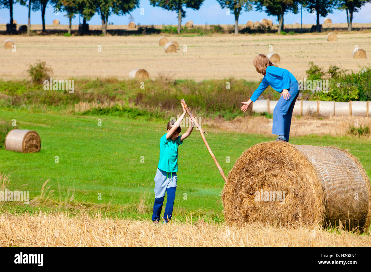 Zwei jungen, die Ballen Heu mit Stick als Hebel bewegen Stockfoto