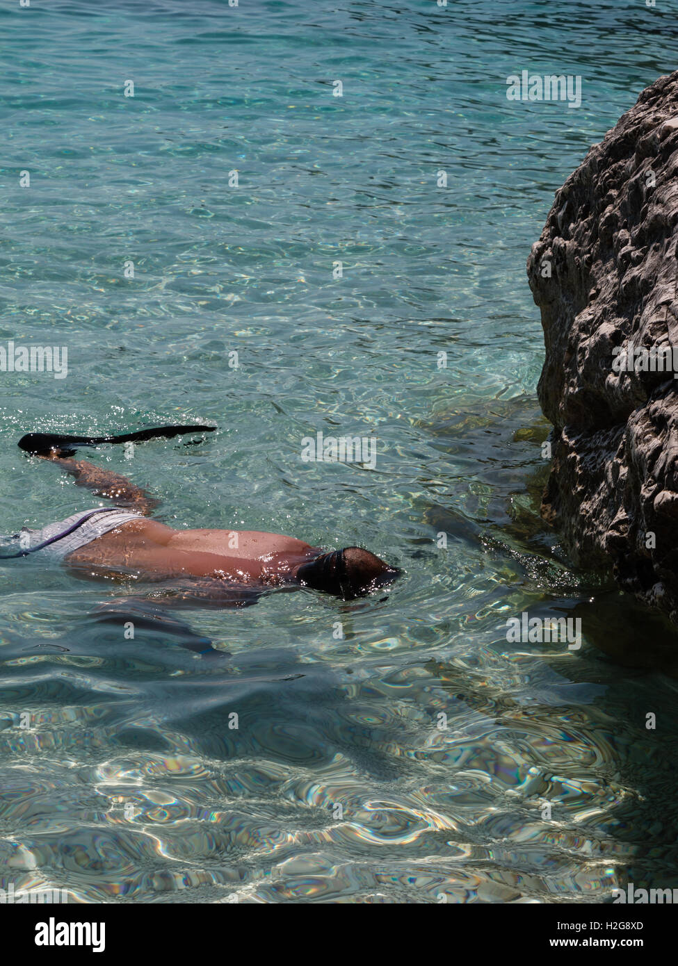 Mann im kristallklaren Meer mit Flossen, Badeanzug und Taucher Maske Stockfoto