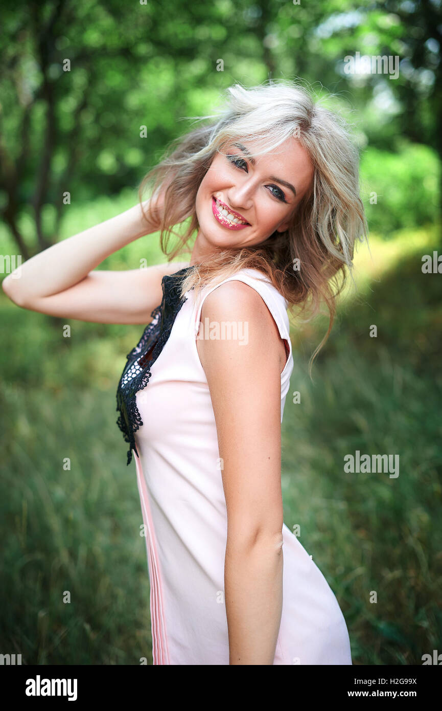 Frau mit langen blonden Haaren posiert im Sommerpark Stockfoto
