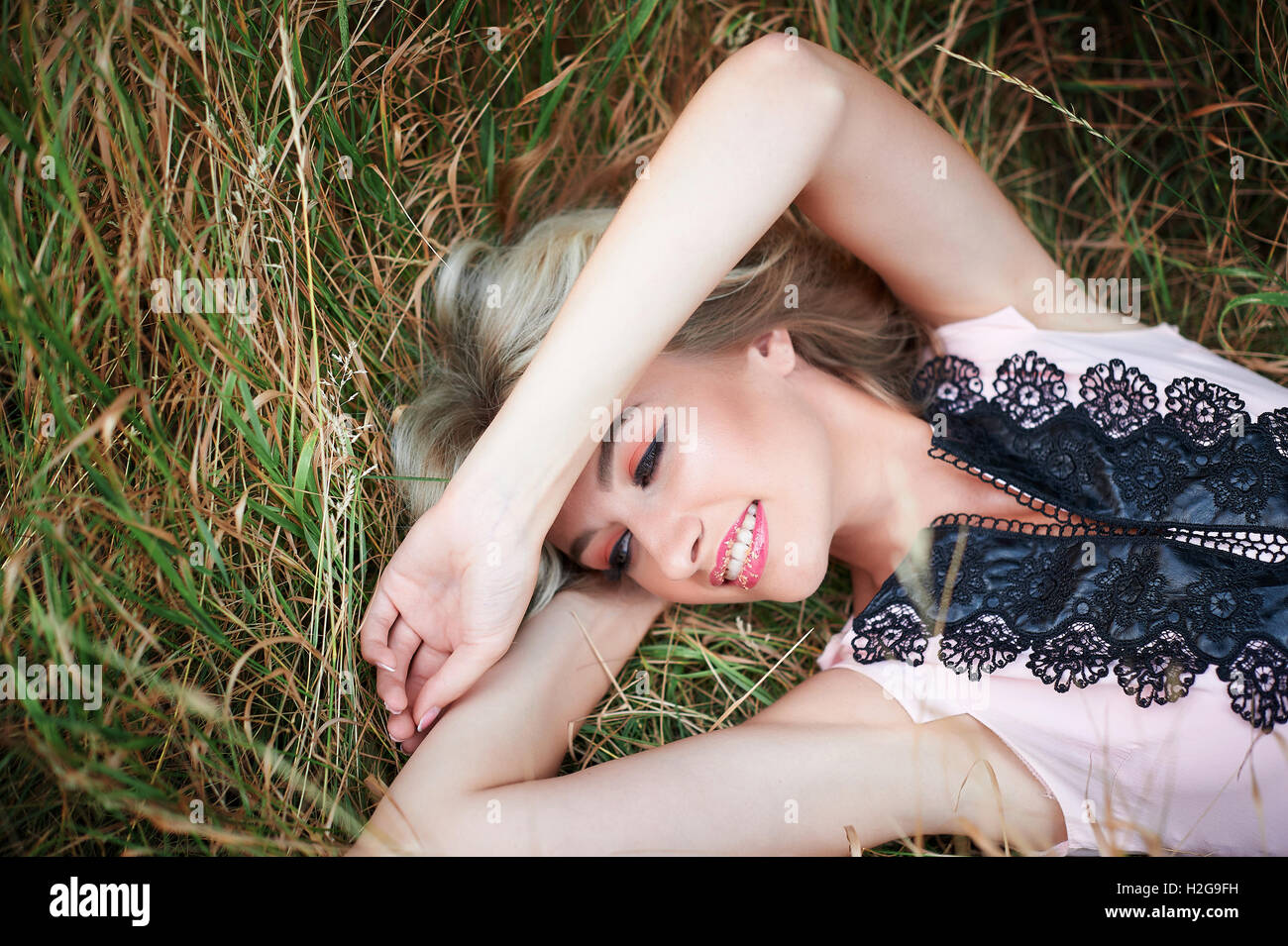 Junge glückliche Frau liegend auf dem Rasen im freien Stockfoto