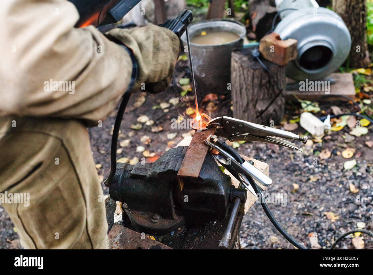 Schweißer Schweißnähte Eisenring durch vor Ort Elektroschweißen in Outdoor-ländlichen Werkstatt Stockfoto