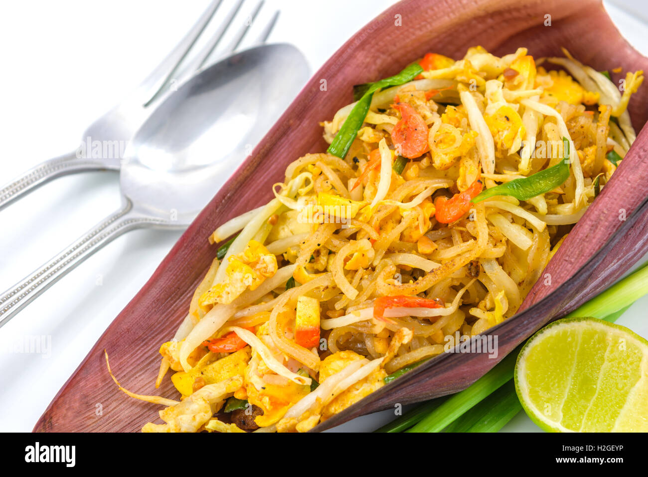 Thai Gebratene Nudeln oder gebraten Thai-Stil kleine Reisnudeln (Pad Thai) auf Banane Blüte mit Gabel und Löffel auf weiß Stockfoto