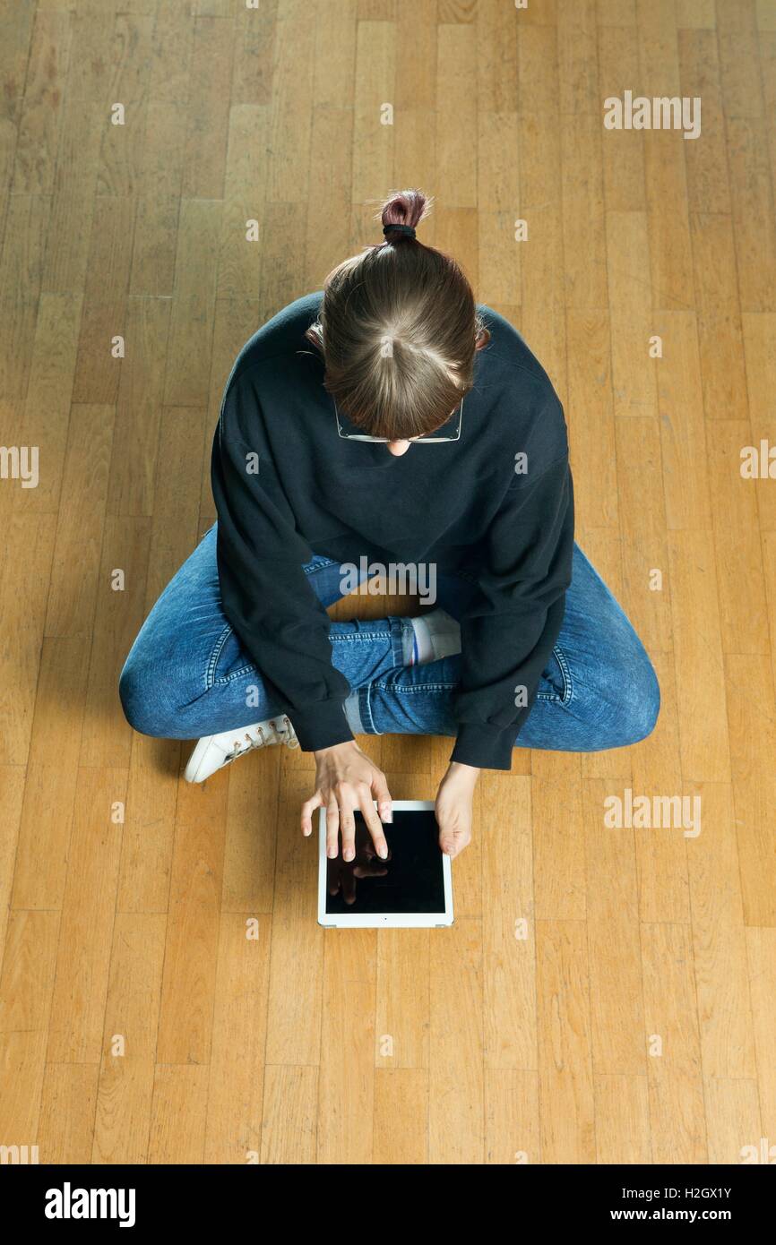 Frau, die mit ihrem Tablet-PC sitzt auf einem Holzfußboden in Topview Perpective erfasst | weltweite Nutzung Stockfoto