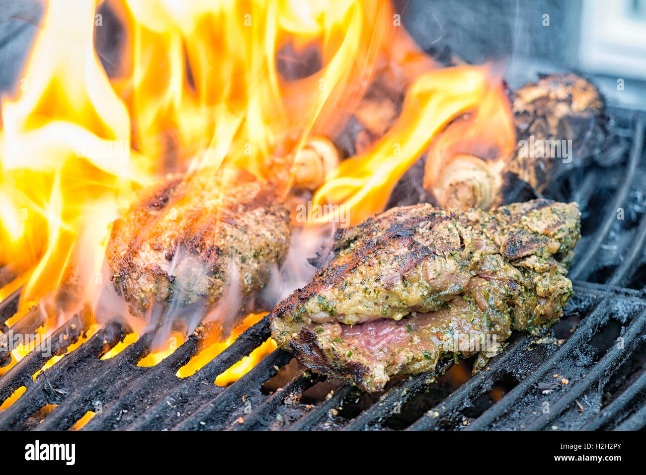 Marinierte Steaks auf dem Grill Flammen aus der das Fett, das Fleisch in den Grill tropft. Stockfoto