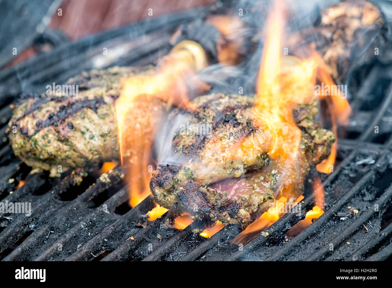 Stück Fleisch auf dem Grill, Flammen präsentieren sich ihnen Stockfoto