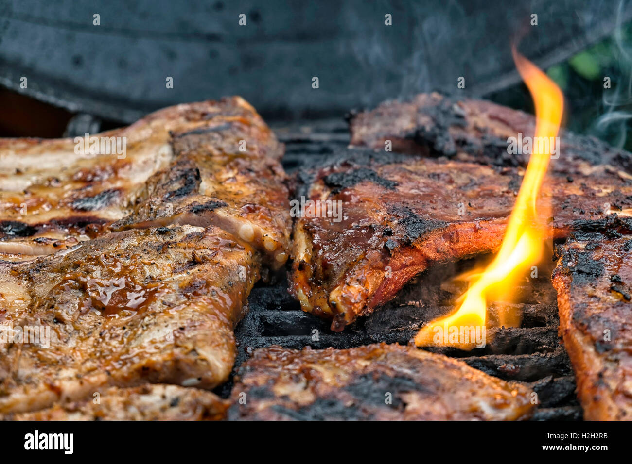 Stück Fleisch auf dem Grill, Flammen präsentieren sich ihnen Stockfoto