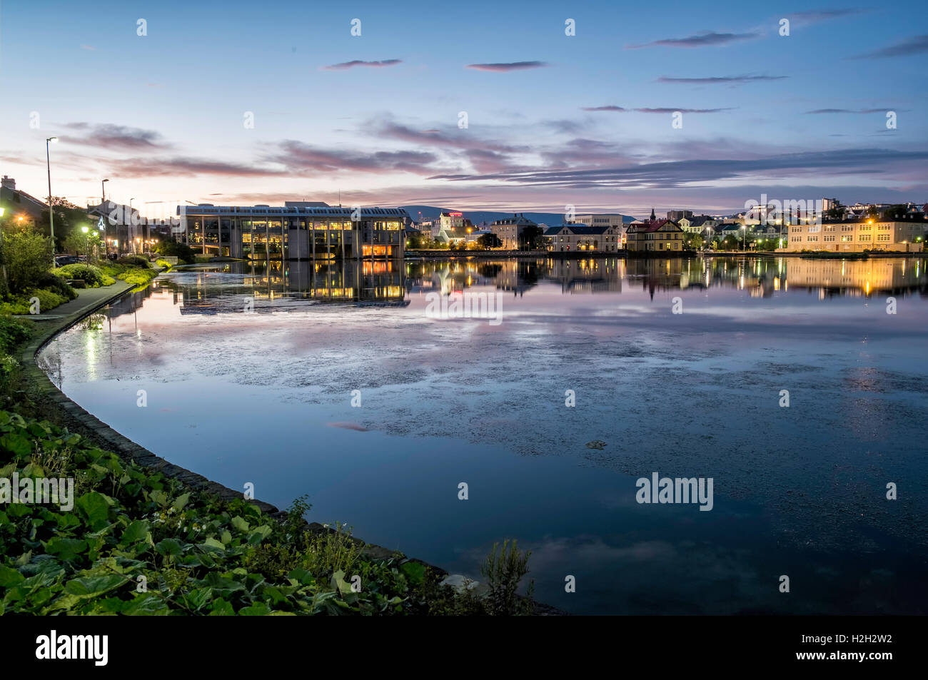 Reykjavik Teich erschossen auf einem noch Sommernacht, Rathaus von Reykjavik und andere Häuser spiegeln sich in das Stille Wasser. Stockfoto