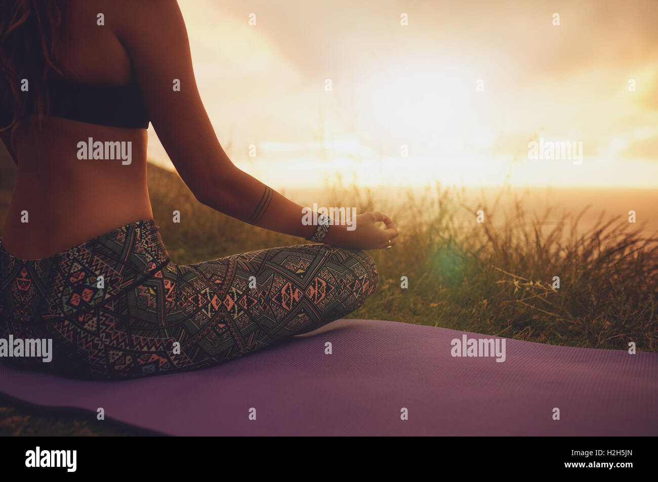 Nahaufnahme einer Frau, die in Lotus-Yoga-Pose auf der Trainingsmatte sitzt, mit Fokus auf die Hände. Fitness-Frau, die im Freien meditiert Stockfoto