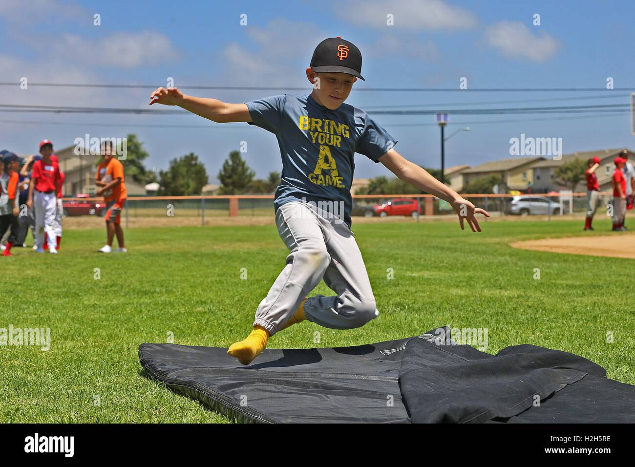Ein kleiner Junge gleitet in einer Schaummatte während einer Sommer-Baseball-Camp mit ehemaliger professioneller Baseballspieler Adrian Burnside an den Draht-Berg-Baseball-Feld 12. Juli 2016 in Camp Pendleton, Kalifornien. Stockfoto