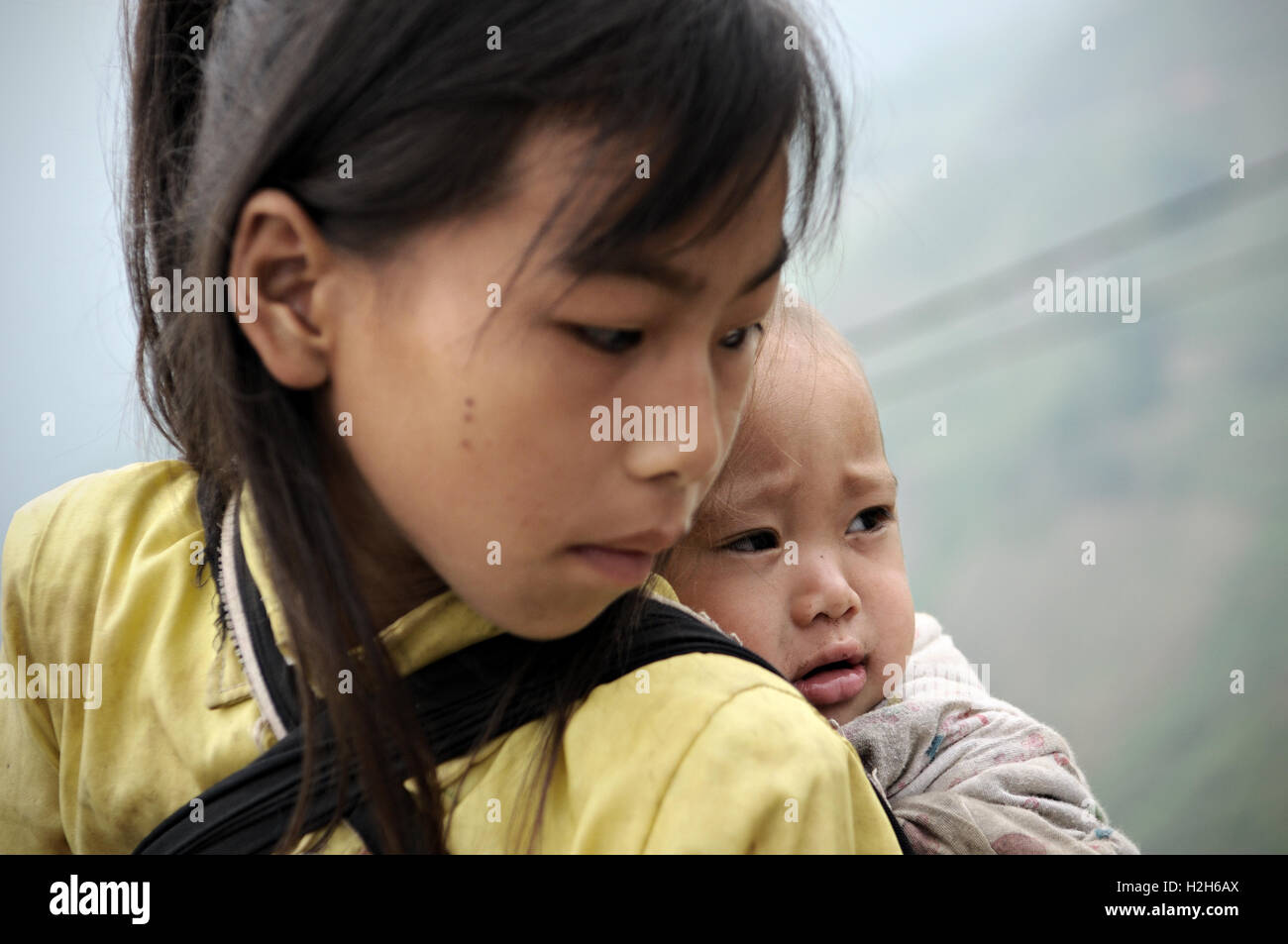 Baby auf dem Rücken ihrer Schwester in der Provinz Ha Giang, Nord-Vietnam Stockfoto