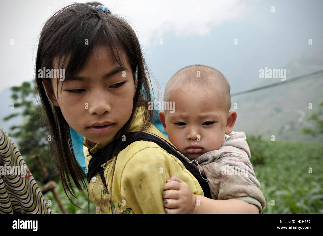 Junges Mädchen mit ihrem Bruder auf dem Rücken in der Provinz Ha Giang, Nord-Vietnam Stockfoto