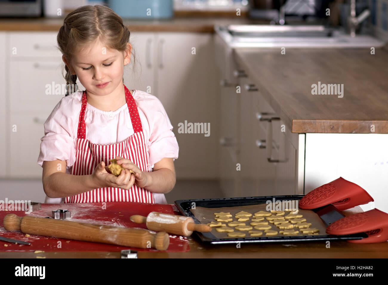 Ein Mädchen schneiden Formen der Verknüpfung Herstellung Kekse Gebäck Stockfoto
