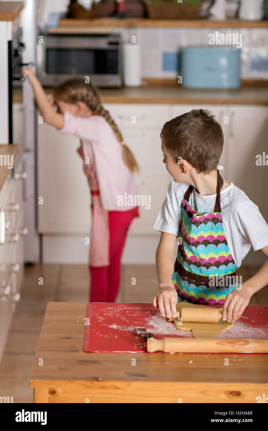 Junge schaut Mädchen, das wartet auf die Kekse im Ofen kochen Stockfoto