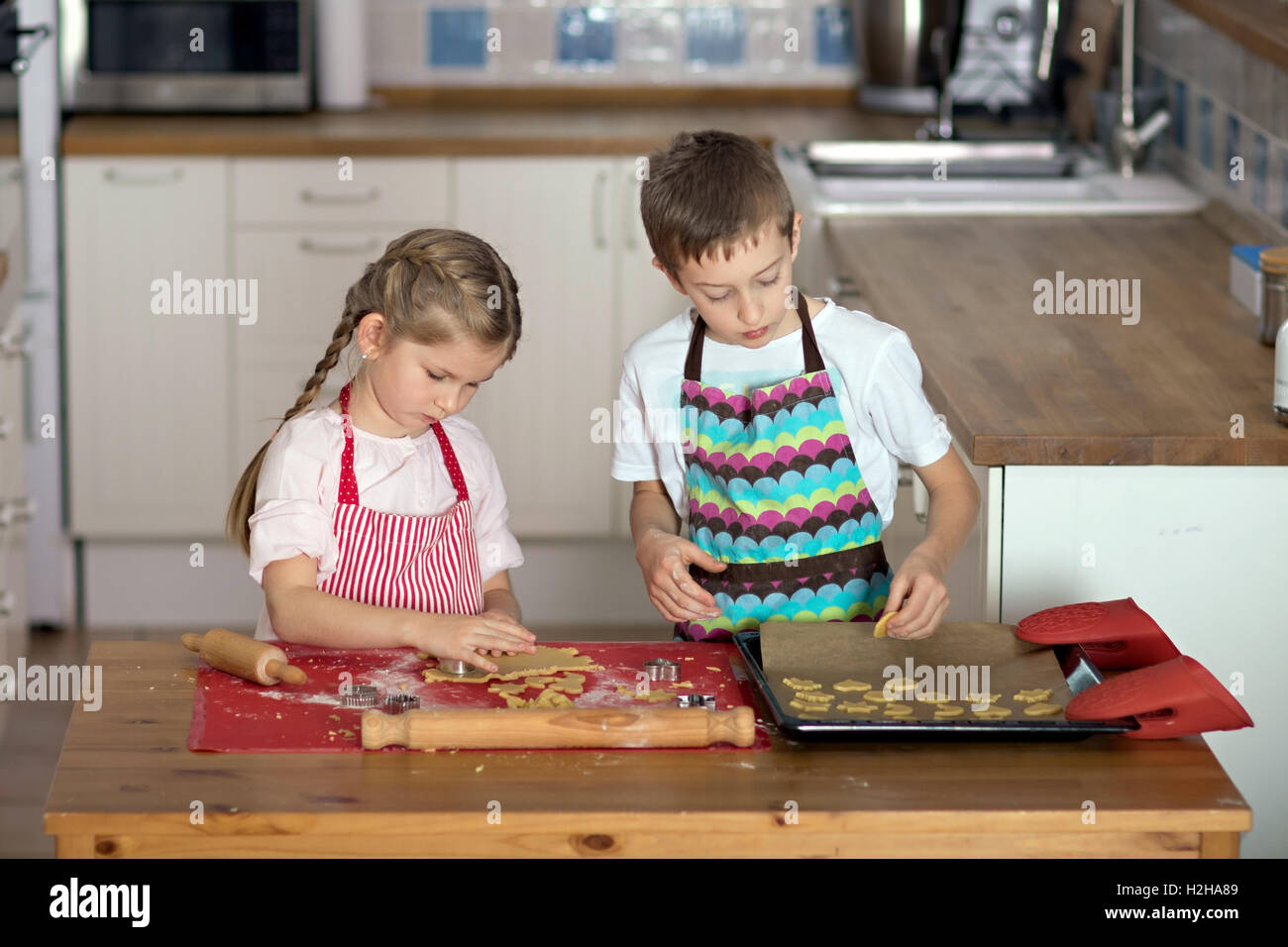 Mädchen und jungen Schnittformen der Verknüpfung Backwaren Herstellung Kekse in der Küche Stockfoto