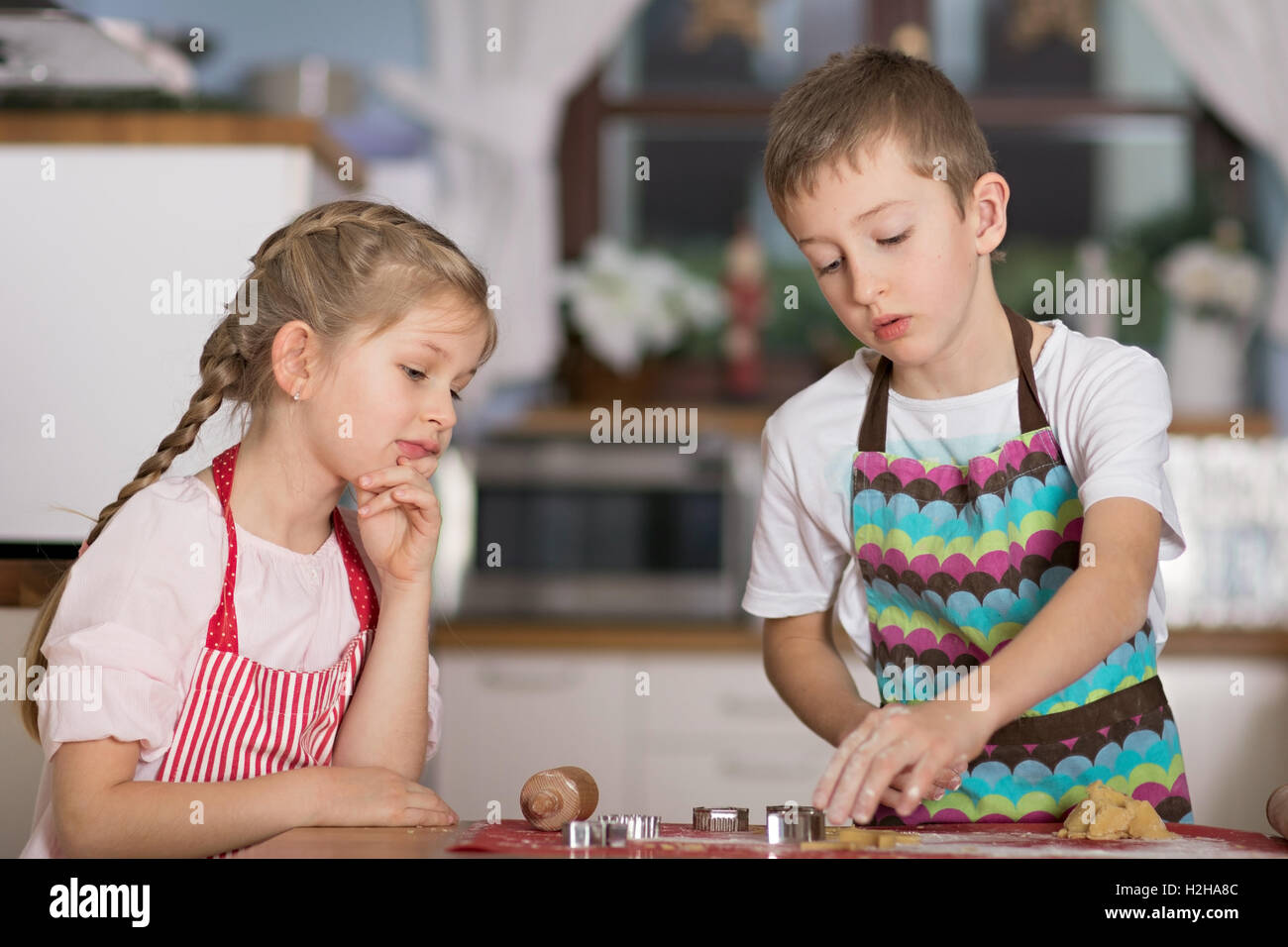 Mädchen junge Kekse Formen von einigen Gebäck in der Küche in ihrem Haus zu schneiden-Uhren Stockfoto