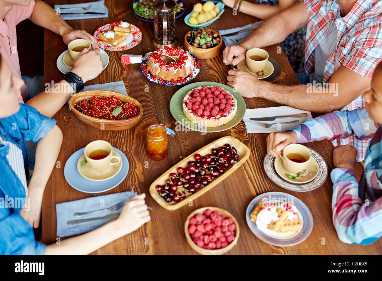 Verschiedene leckere Essen am Tisch und Gruppen von Freunden zu Abend essen Stockfoto