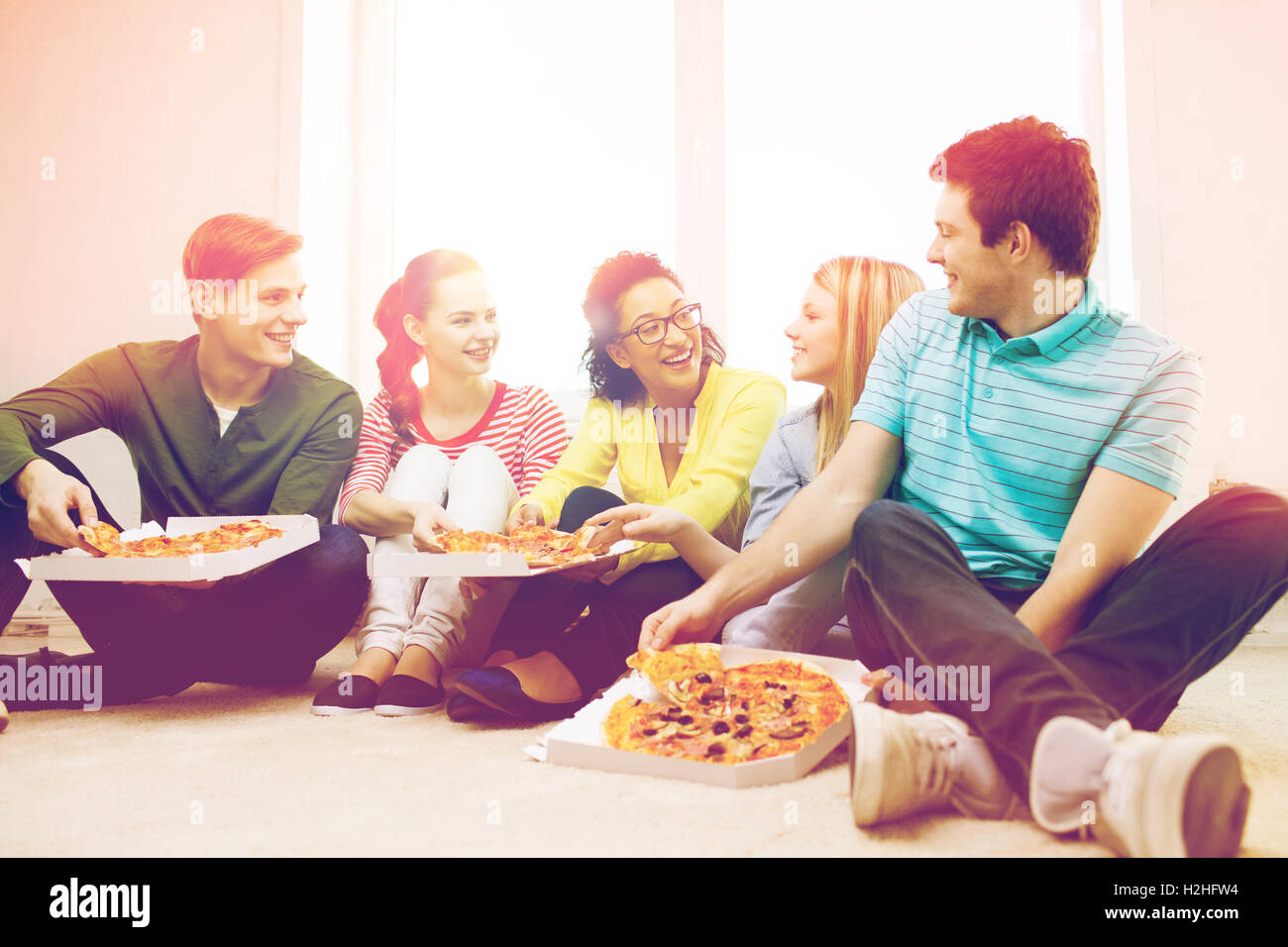 fünf lächelnde Teenager Essen Pizza zu Hause Stockfoto