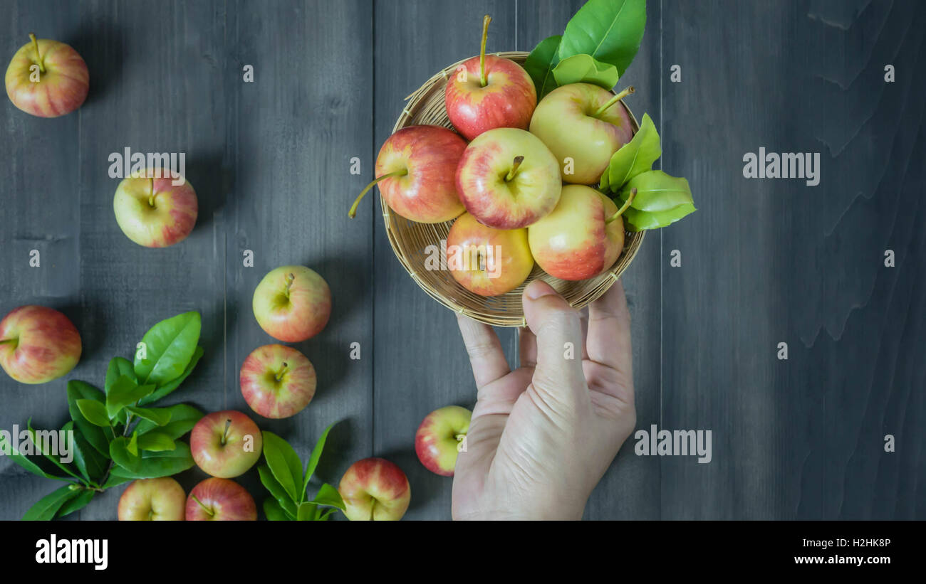 menschliche Hand, die roten und gelben Apfel auf hölzernen Hintergrund, Ansicht von oben Stockfoto