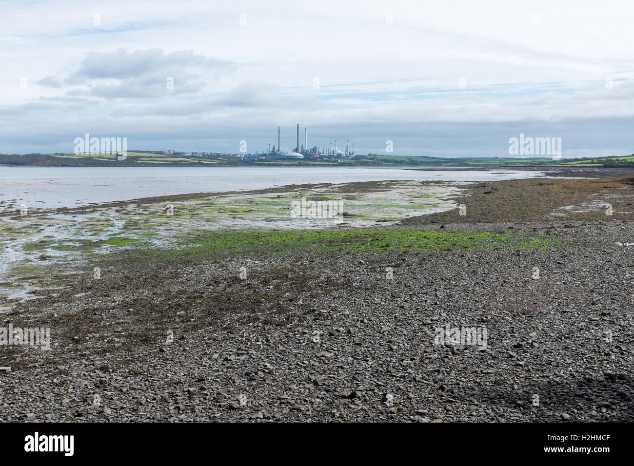 Stoney Strand bei Ebbe am Pembroke mit Milford Haven Power Station in der Ferne, Pembrokeshire, Wales Stockfoto