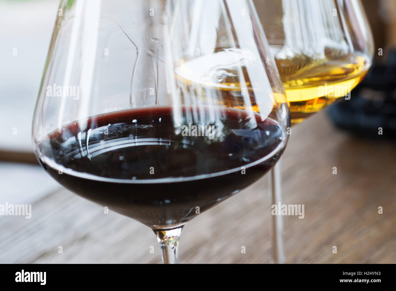Gläser von roten und weißen Wein schließen sich auf hölzernen Hintergrund Stockfoto