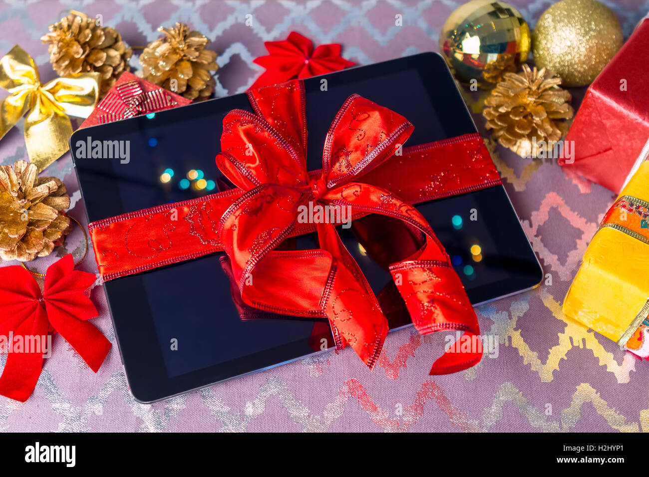Tablet-pc zu Weihnachten mit Geschenken, Dekorationen auf Tisch. Stockfoto