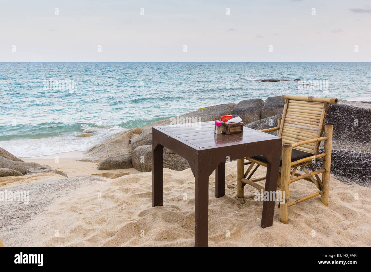 Tisch und Stuhl auf einem sandigen Spot gerade in den Felsen, neben dem Meer Stockfoto