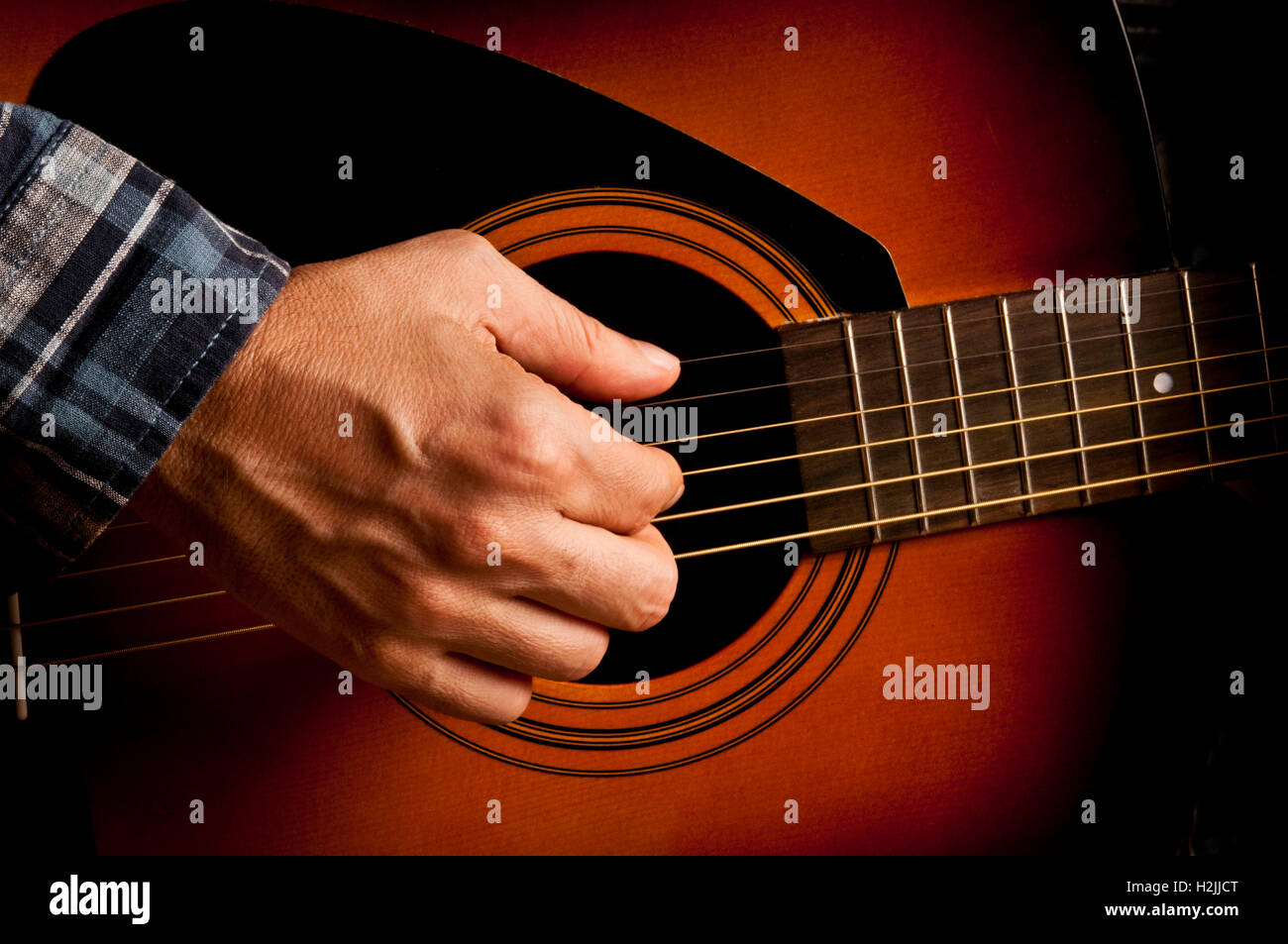 männliche Gitarrist spielt eine akustische Gitarre Stockfoto