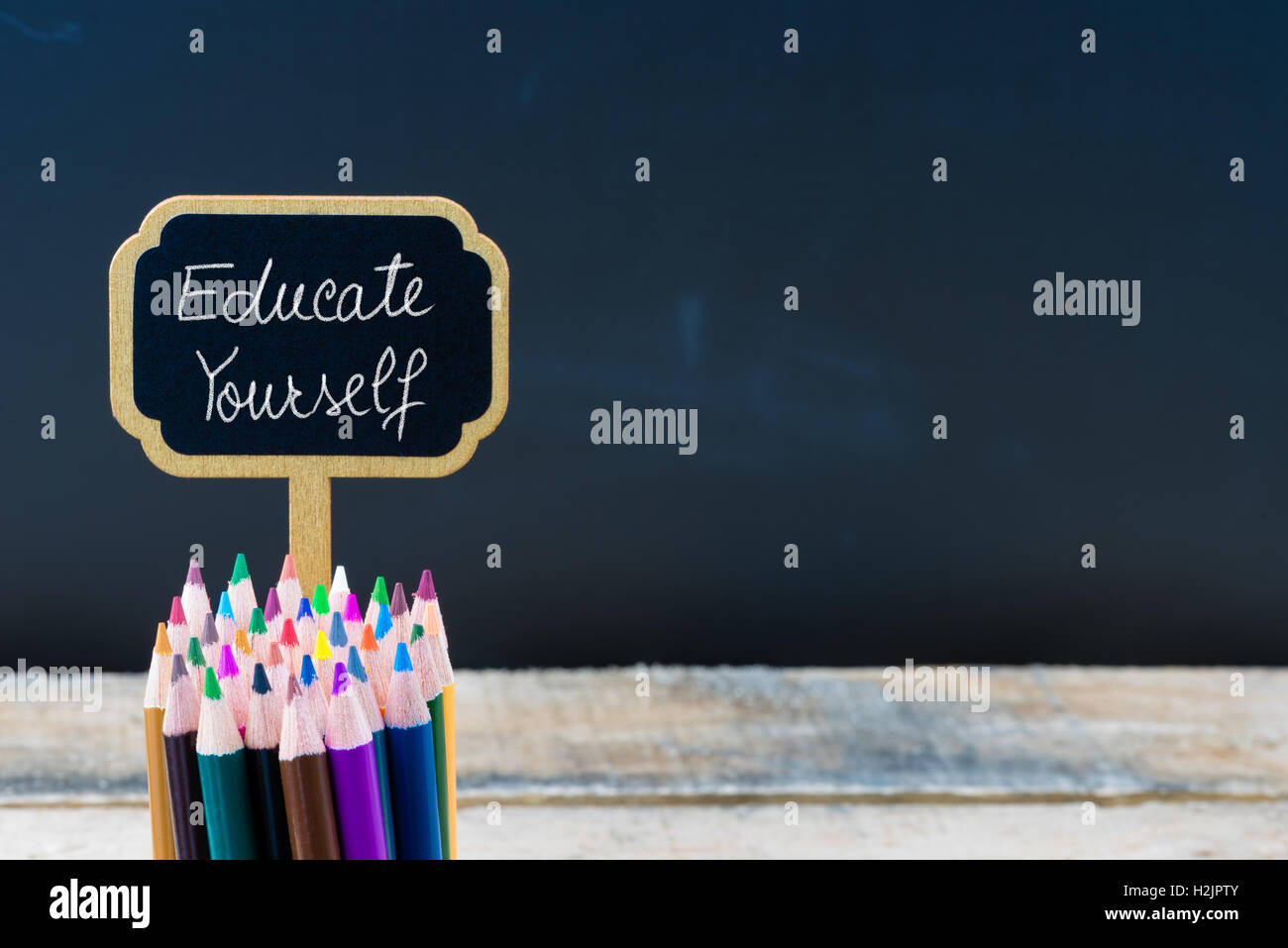 Hölzerne Mini Tafel Label mit Nachricht informieren Sie sich und Buntstifte über Tafel Hintergrund Stockfoto