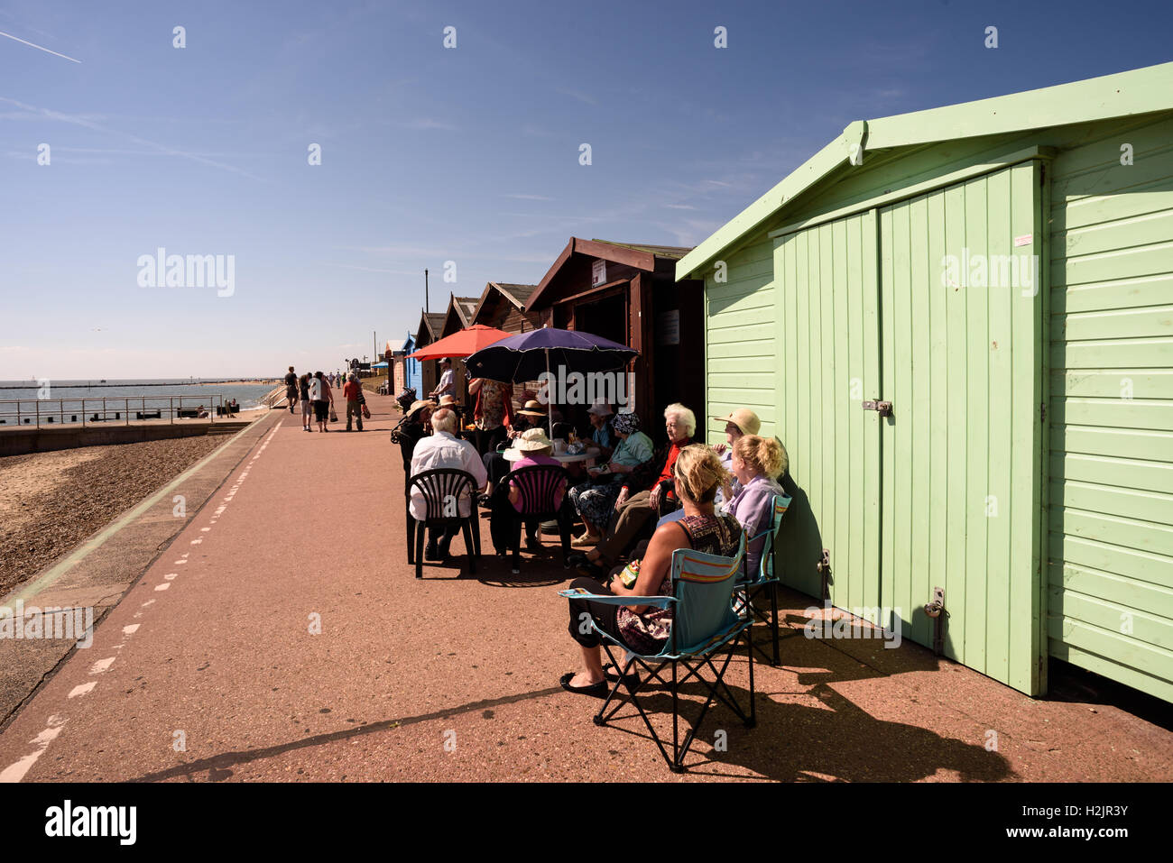 Gruppe älterer Menschen sitzen außerhalb einer hölzernen bemalten Strandhütte Orangensaft trinken, im Sommer 2016 Stockfoto