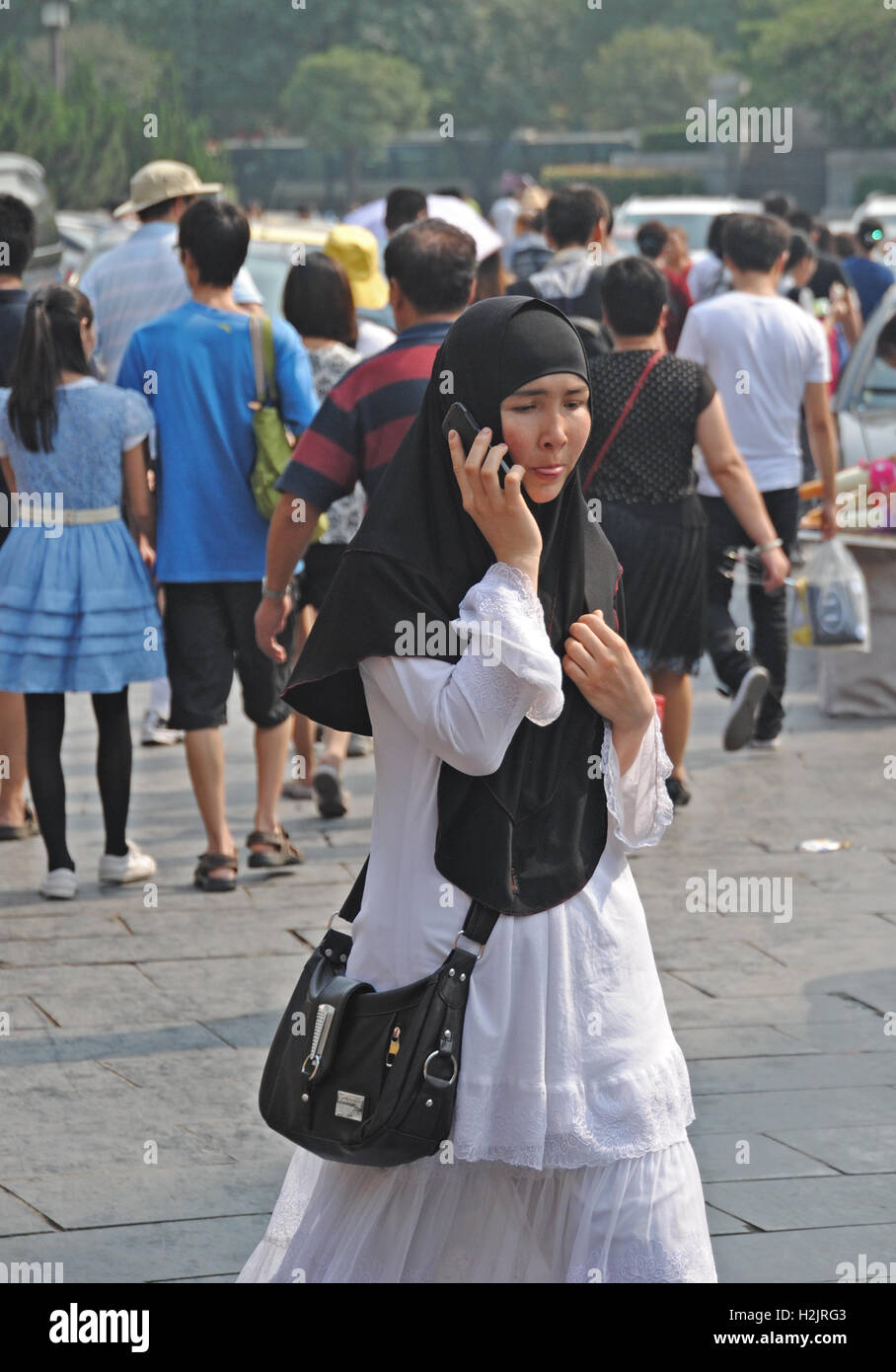 Ein chinesisches muslimische Mädchen tragen ihre Kopfbedeckung nimmt einen Anruf, wie sie durch die alte Hauptstadt Xian, China Spaziergänge. Stockfoto