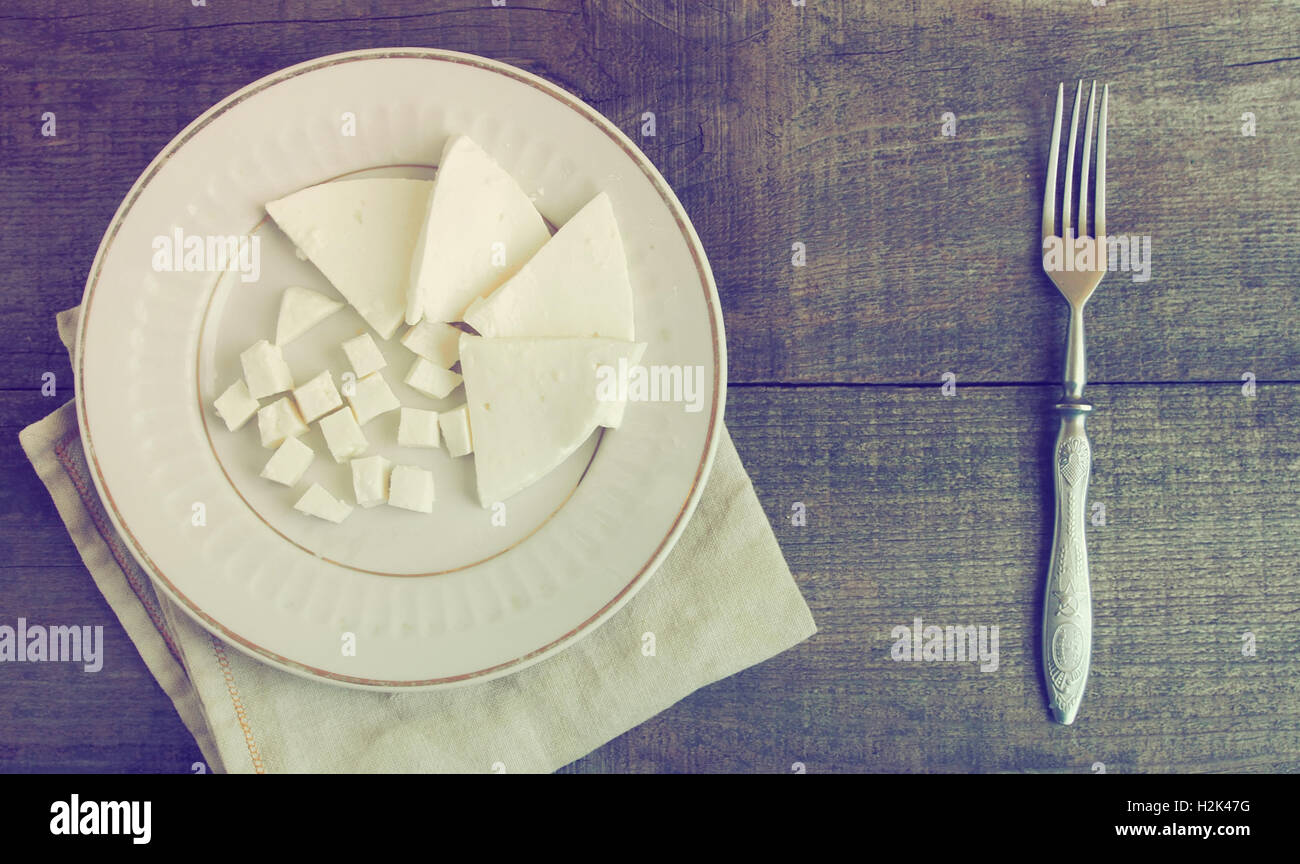 Stücke von weißer Käse auf Platte und Vintage-Gabel über hölzerne Hintergrund. auf rohem Holz Hintergrund. Grunge-Stil. Stockfoto