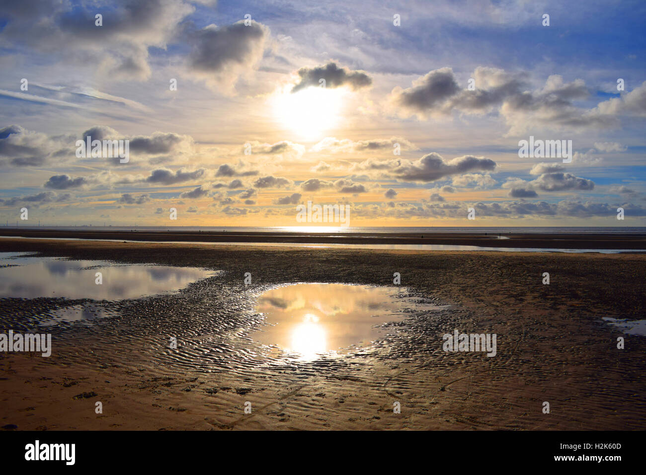 Sonne am Himmel über Sandstrand bei Flut Stockfoto