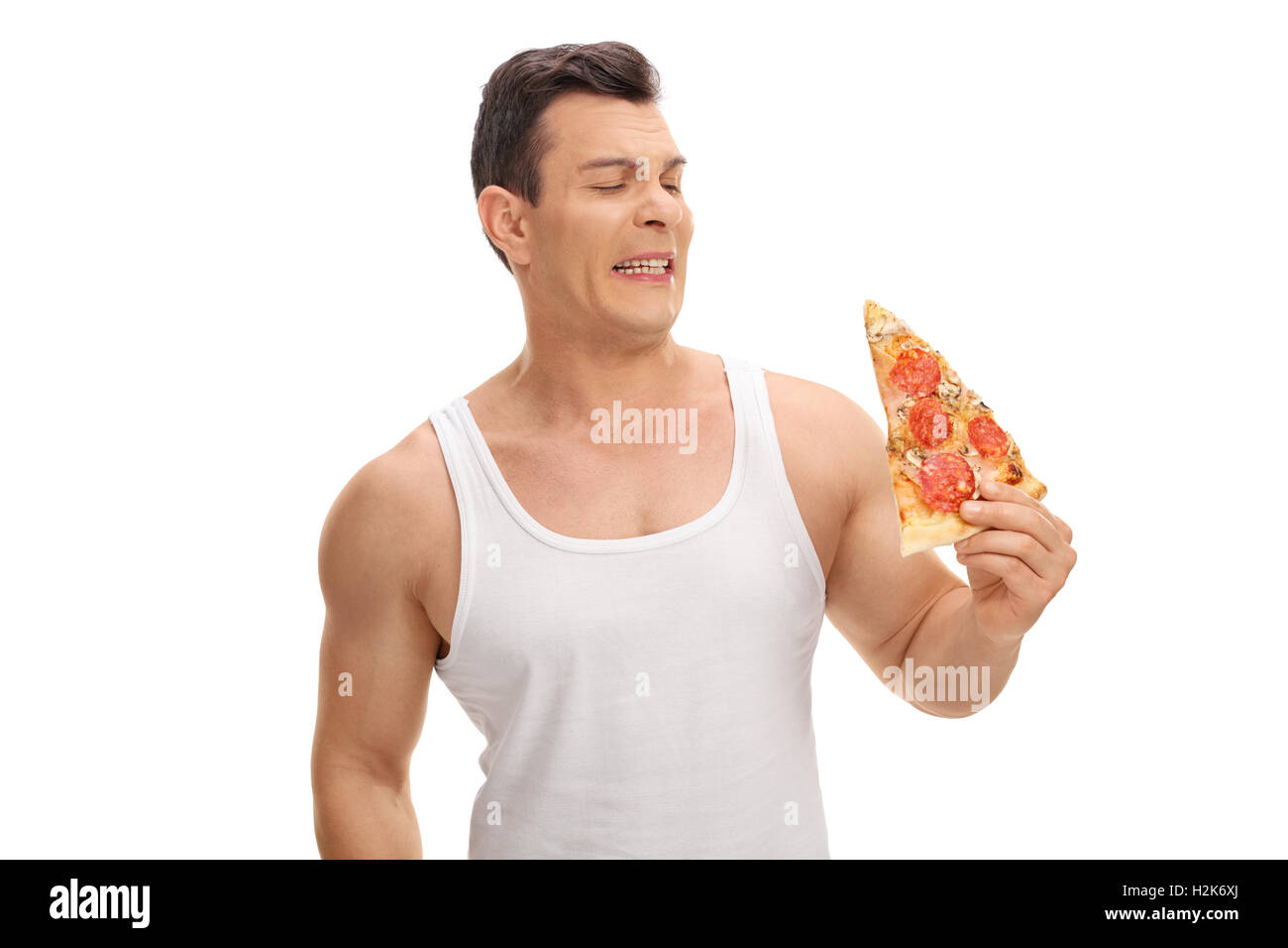 Angewidert junger Mann, Blick auf ein Stück Pizza isoliert auf weißem Hintergrund Stockfoto