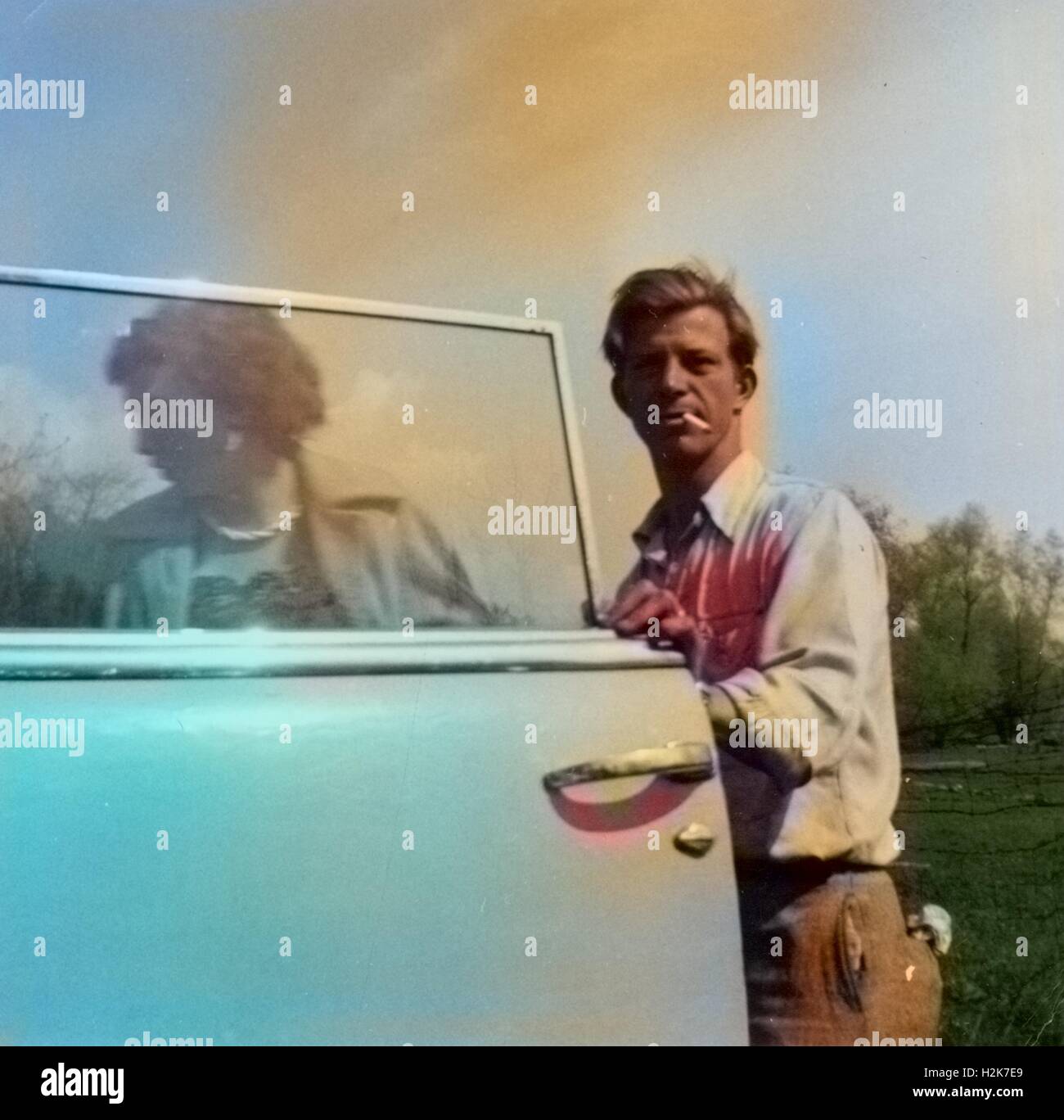 Unbekannte Stadt, USA - 1. Januar 1953: Digital eingefärbt Vintage Foto eines Mannes halten Öffnen einer Autotür für eine Frau beim Rauchen einer Zigarette, 1953 Stockfoto