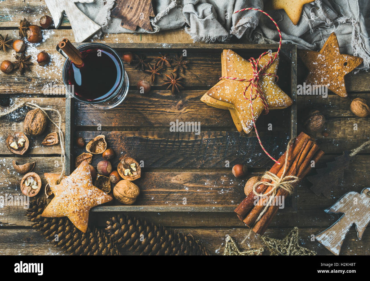 Glas Glühwein in Holztablett mit Weihnachten Dekoration Spielzeug, Lebkuchen, Nüssen, Zimt, Anis, Puderzucker und Stockfoto