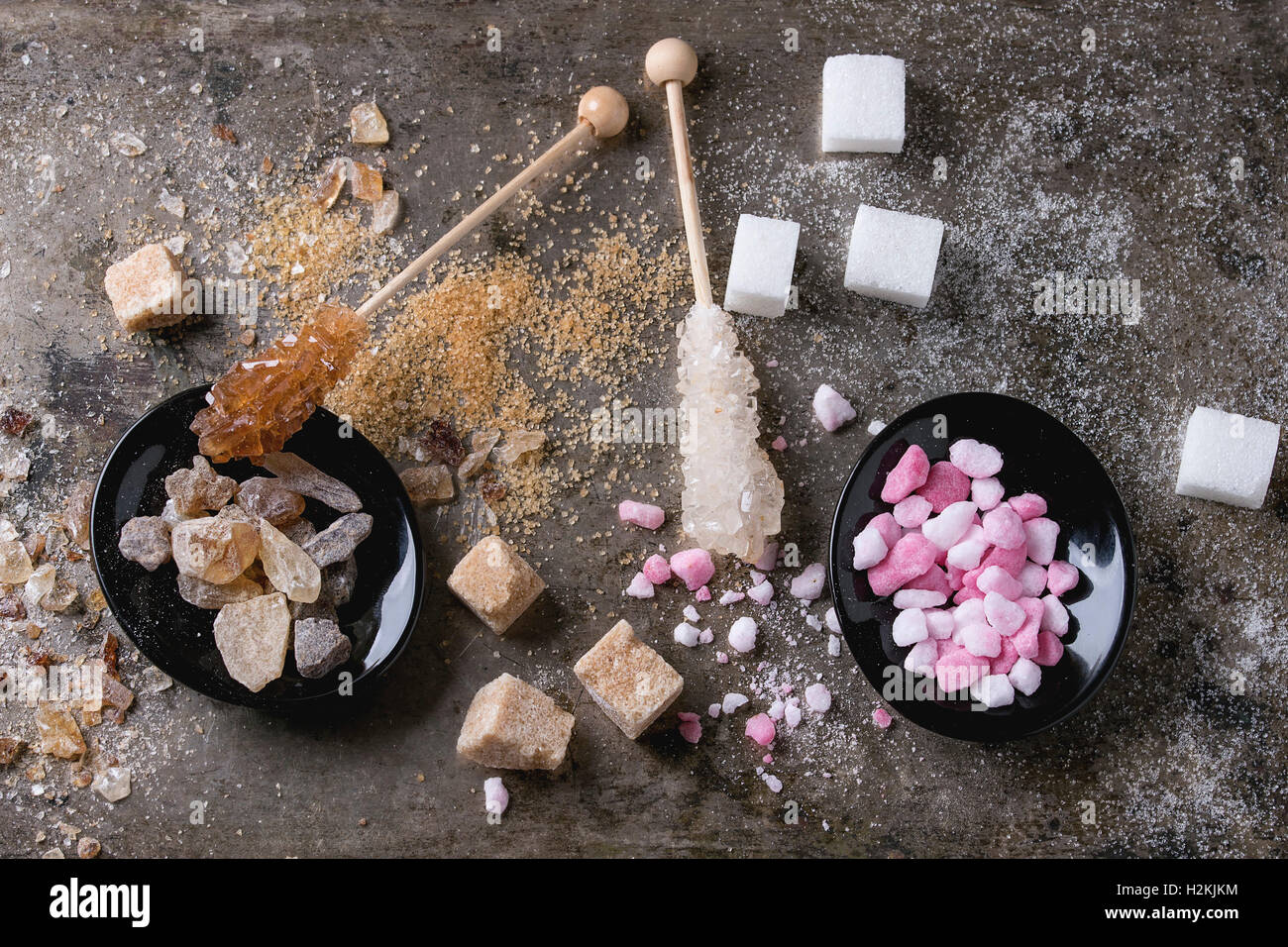 Vielzahl von Zucker weiß, braun, rosa Früchte granuliert, Würfel und Kristall über alte Textur Eisen Hintergrund. Ansicht von oben. Stockfoto