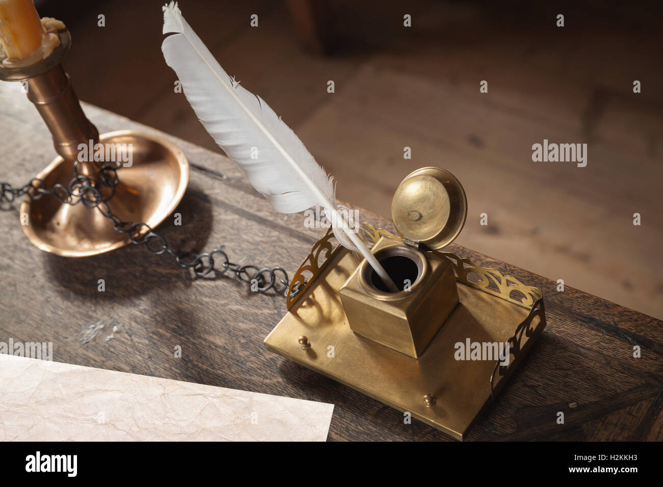 Alten Schreibzeug auf Holztisch. Messing-Tintenfass, weißer Stift und Altpapier Stockfoto