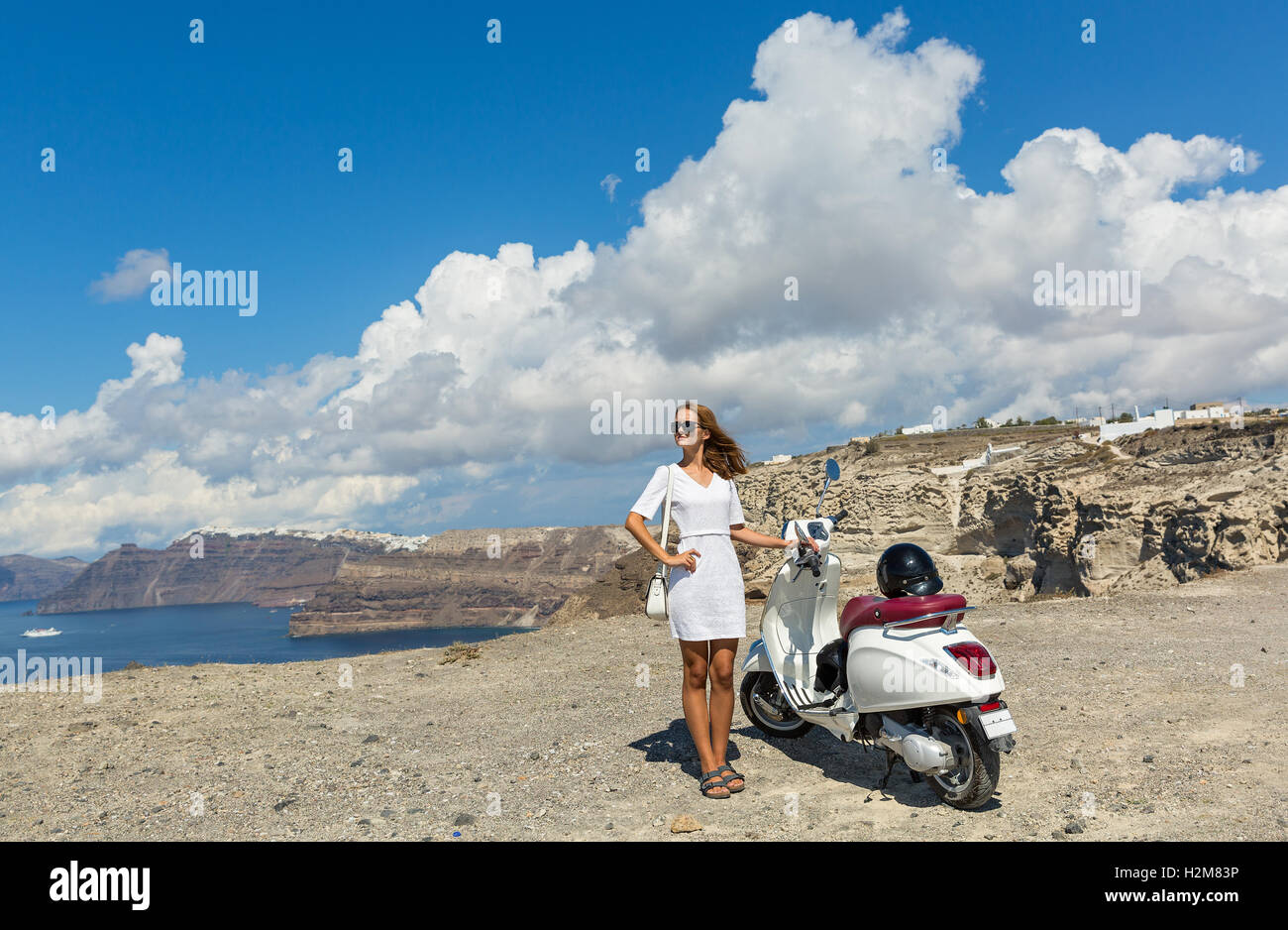 Junge Frau mit weißen Motorrad auf dem Hügel über dem Meer Stockfoto
