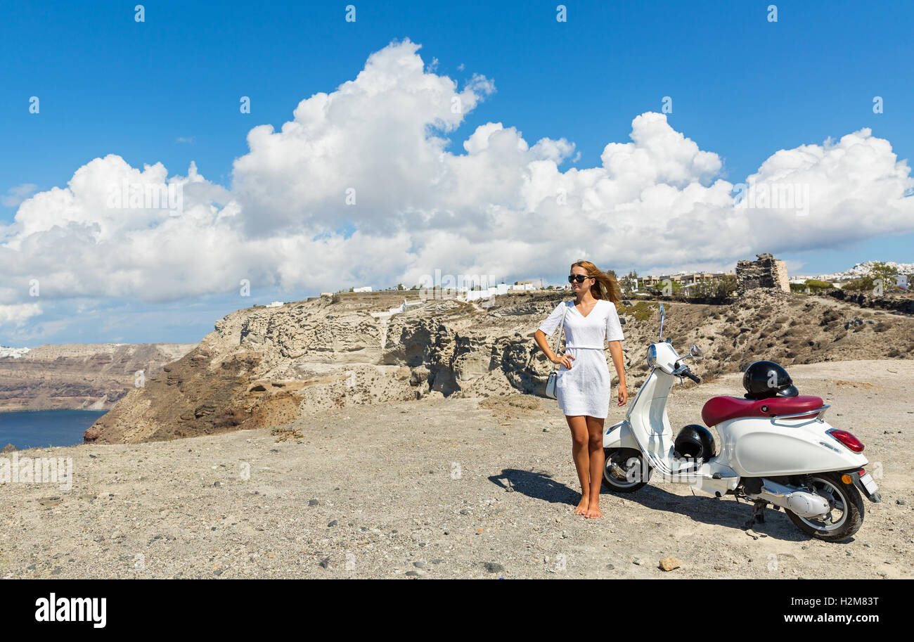 Junge Frau mit weißen Motorrad auf dem Hügel über dem Meer Stockfoto