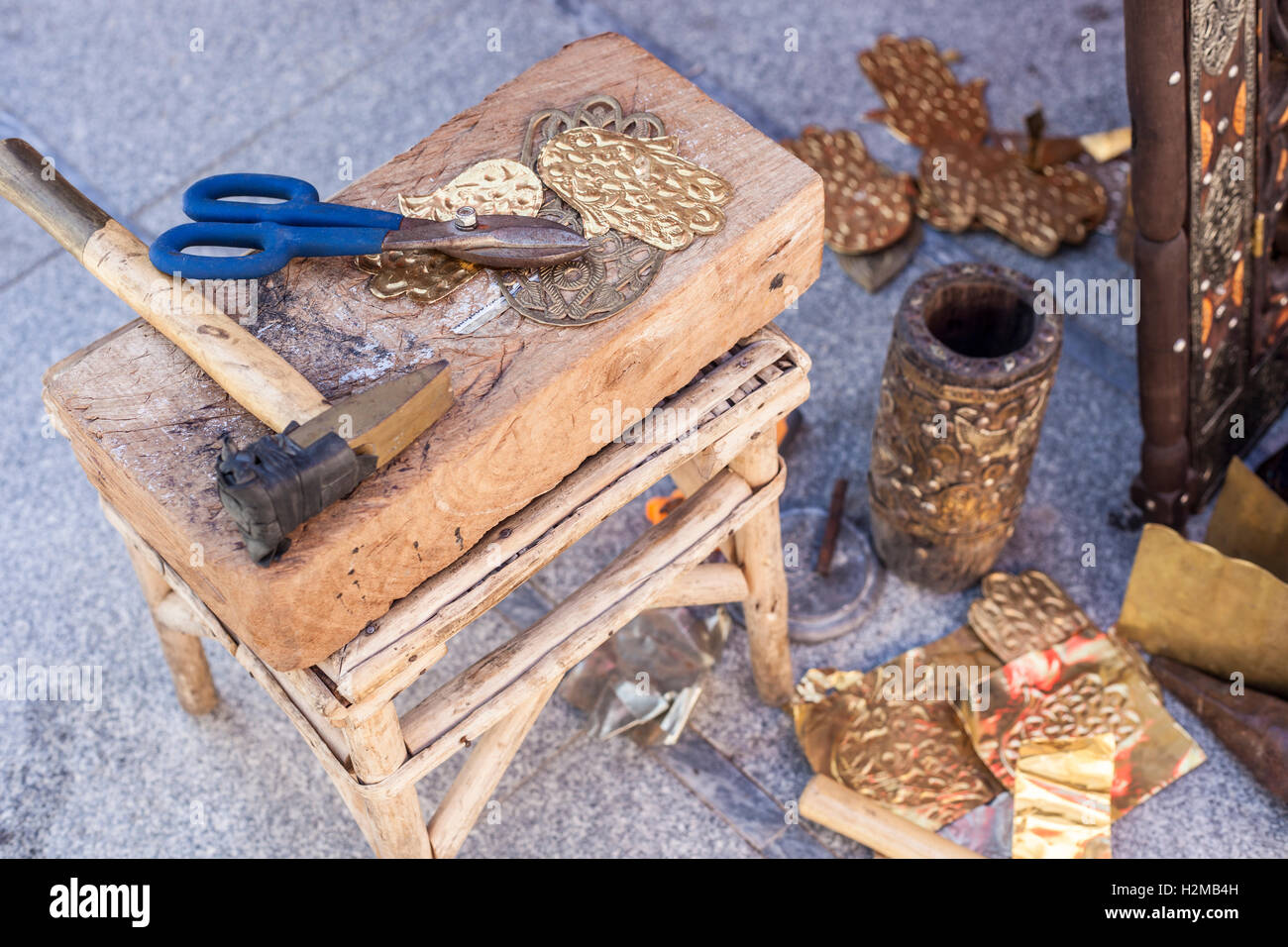 Handwerker-Bank mit Werkzeugen für Gravieren Hamsa Palm-förmigen Messing Amulette Stockfoto