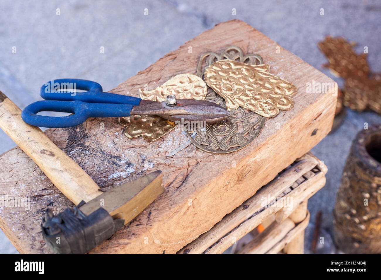 Handwerker-Bank mit Werkzeugen für Gravieren Hamsa Palm-förmigen Messing Amulette Stockfoto