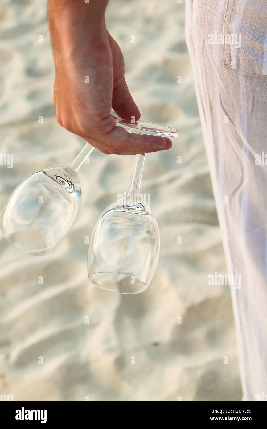 Nahaufnahme von zwei Gläsern in der Hand bei Man barfuß am Strand Stockfoto