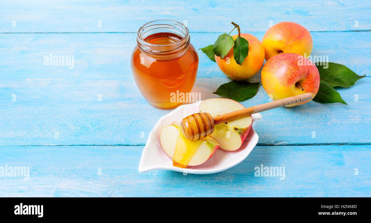 Honig Glas und Apfel Scheiben mit Honig auf blauem Hintergrund aus Holz. Rosch ha-Schana Konzept. Jewesh neue Jahr Symbole. Kopieren Sie Raum. Stockfoto